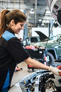 Young female mechanic wiping the engine oil dipstick