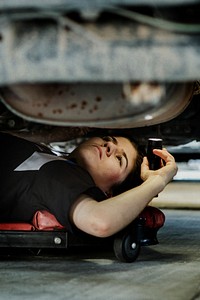 Female mechanic checking the undercarriage of a car