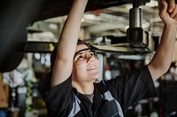 Female mechanic checking the undercarriage of a car