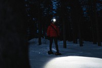 Woman with headlights exploring the woods at dusk