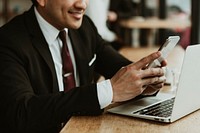 Happy businessman using his phone in a cafe