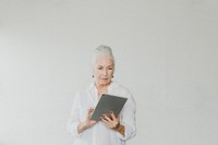 Senior woman using a digital tablet in a white room