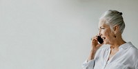 Cheerful senior woman talking on a phone in a white room
