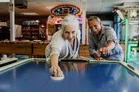 Happy senior couple enjoying a game of table hockey inside of a game arcade