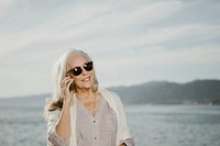 Senior woman talking on the phone by the sea