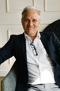 Portrait of a cheerful aged businessman sitting on a couch