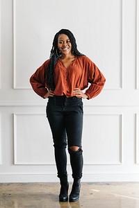 Happy empowering black woman standing by a white wall