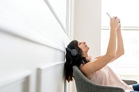 Woman wearing headphones and taking a selfie