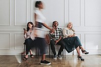 Diverse people sitting by a white wall