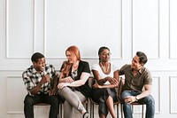 Happy people sitting by a white wall