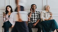 Diverse people sitting by a white wall