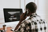 Black businessman talking on the phone while using the computer