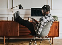 Black man with headphones playing on his phone sitting at his desk