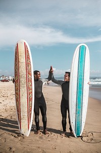 Happy surfers doing a high five on the beach