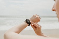 Woman checking her smartwatch on the beach