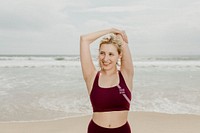 Young happy woman stretching by the beach