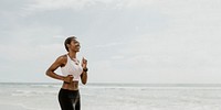 Happy black woman jogging on the beach
