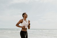 Happy black woman jogging on the beach