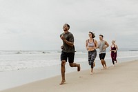 Happy friends jogging together at the beach