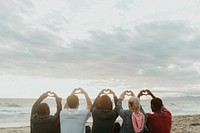 Friends making love heart hands at the beach