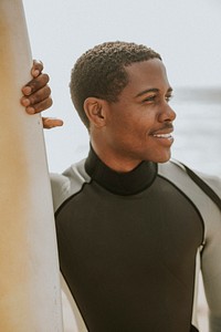Black man standing by the surfboard