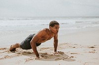 Muscular black man doing pushups at the beach