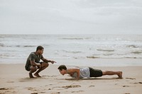 Man doing pushups with a trainer at the beach