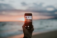 Man taking a picture of the sunset on the beach