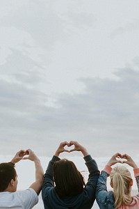 Friends making love heart hands at the beach