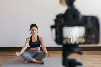 Yoga blogger recording a video while in a padmasana pose