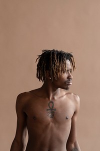 Black tattooed man posing by a beige background