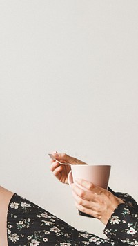 Woman sitting by a white wall with a cup of tea