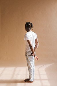 Black man standing by a beige background