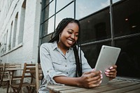 Black happy woman using a digital tablet outdoors