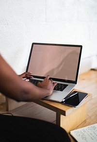 Black woman using a laptop on a wooden table