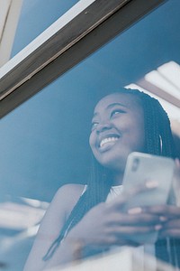 Cheerful black woman texting on her phone