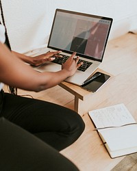 Black woman using a laptop on a wooden table