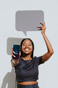 Cheerful black woman showing a blank speech bubble with a phone mockup