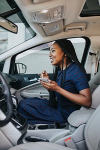 Happy black woman with her phone in the car