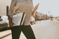 Black woman with file folders crossing a street while using her phone
