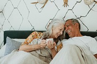 Cheerful elderly couple having a morning coffee in bed
