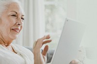 Elderly woman using a tablet on a couch