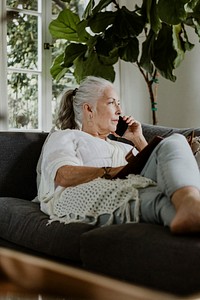Elderly woman lying and talking on a phone on a couch