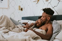 Black couple in bed using a smartphone