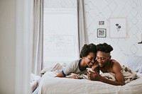 Happy black couple playing on a smartphone in bed