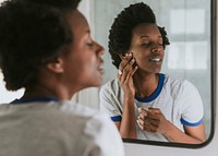 African woman standing by the mirror in the bathroom