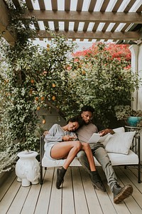 Black romantic couple chilling in the garden with a book