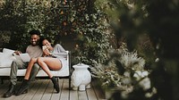 Happy black couple enjoying in the garden with a book and a smartphone