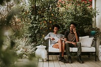 Black couple hanging in the garden with a book and a smartphone