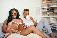 Happy lesbian couple reading a book and drinking coffee